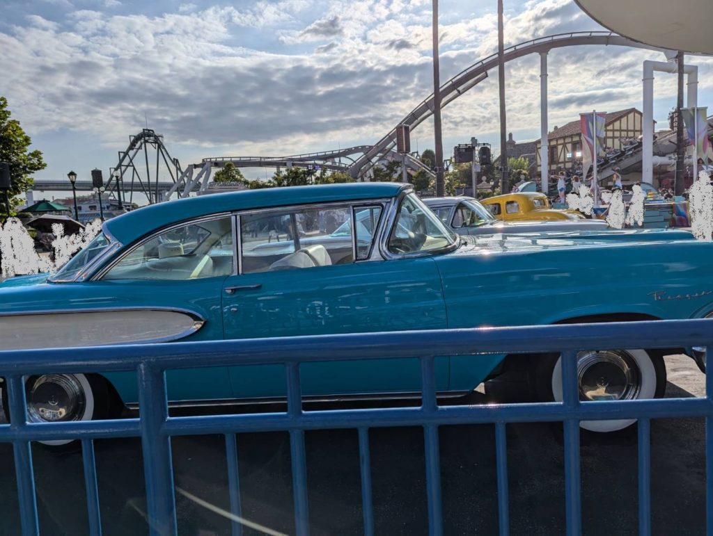 ユニバーサル・スタジオ・ジャパンのメルズ・ドライブイン前に展示された青いクラシックカーを、テラス席から撮影した写真。1950年代のアメリカの雰囲気が漂う。