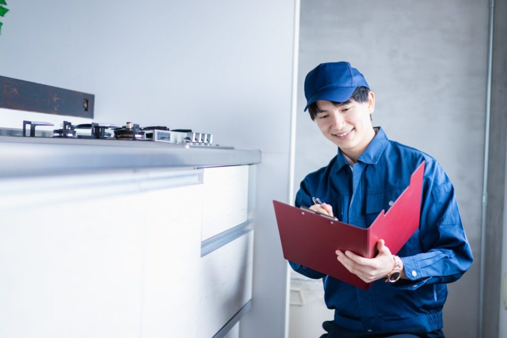 台所で修理作業を行う作業員の写真。食洗器の修理業者に説明を受けるイメージ