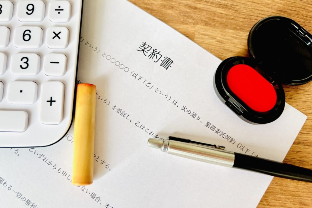 在宅ワークの採用後に交わす契約書と電卓、印鑑、朱肉のイメージ写真