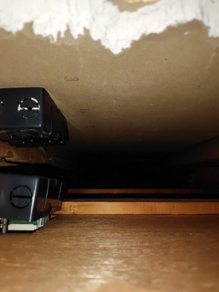 壁の中の柱と電気系統の機械を映した写真