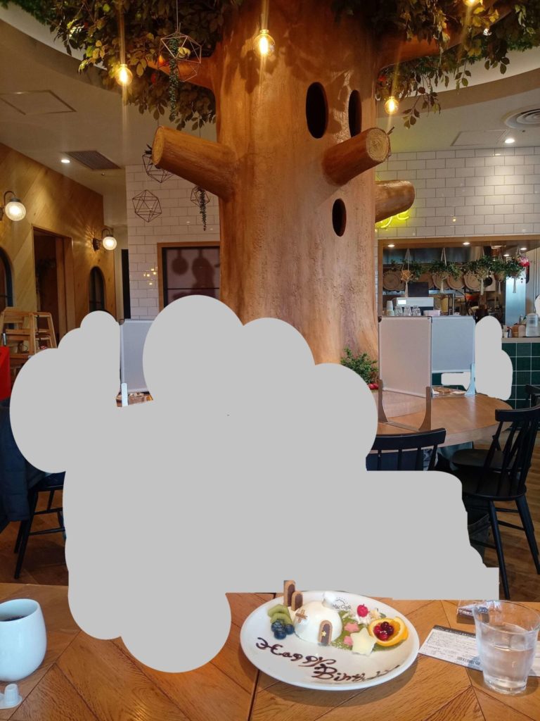 チョコペンでメッセージが書かれたカービィカフェ東京のバースデープレート。ウィスピーウッズのオブジェの前で撮影