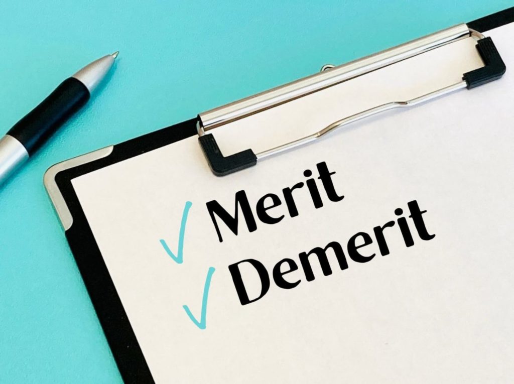 メリット・デメリットと書かれた紙が挟んである黒いバインダーとボールペン